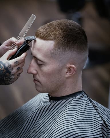 Skin fade in profile, front hairline being detailed with clippers